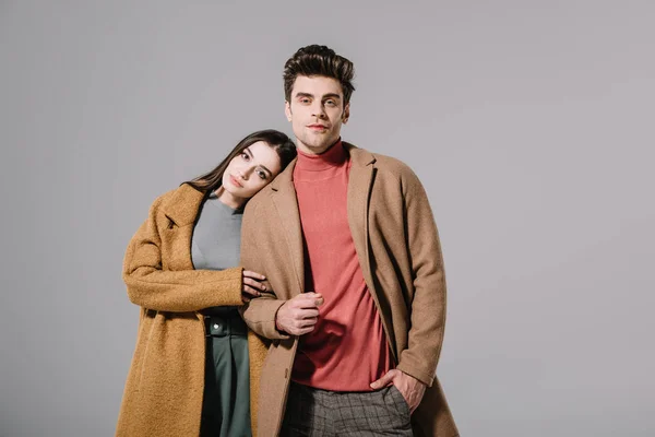 Beautiful stylish couple hugging in beige coats, isolated on grey — Stock Photo