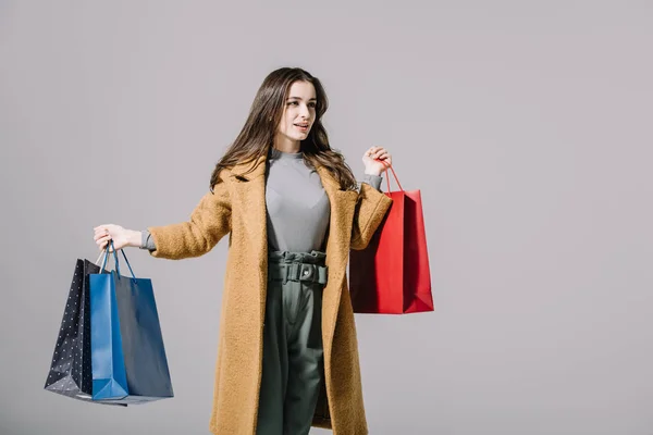Modisches Modell in beigem Mantel mit Einkaufstaschen, isoliert auf grau — Stockfoto