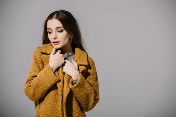 Attractive cold girl posing in warm beige coat, isolated on grey — Stock Photo