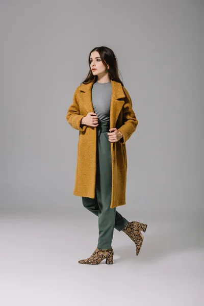 Элегантная женщина позирует в модном бежевом пальто на сером — Stock Photo