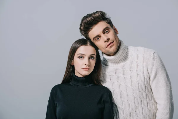 Retrato de pareja elegante posando en suéteres blancos y negros, aislado en gris - foto de stock