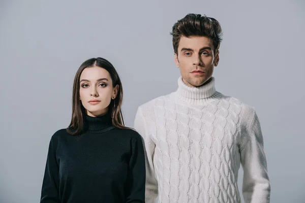 Modisches Paar posiert in weißen und schwarzen Pullovern, isoliert auf grau — Stockfoto