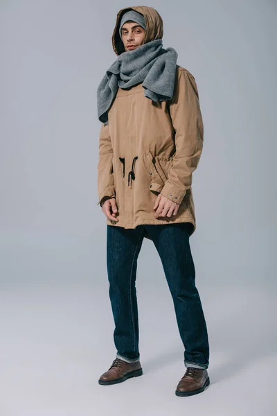 Schöner stylischer Mann posiert mit Hut, Schal und Mantel auf grau — Stockfoto