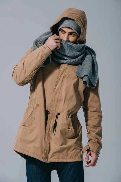 Elegante uomo in posa in inverno cappello, sciarpa e cappotto, isolato su grigio — Foto stock