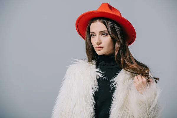 Hermosa mujer elegante posando en abrigo de piel blanca y sombrero rojo, aislado en gris - foto de stock