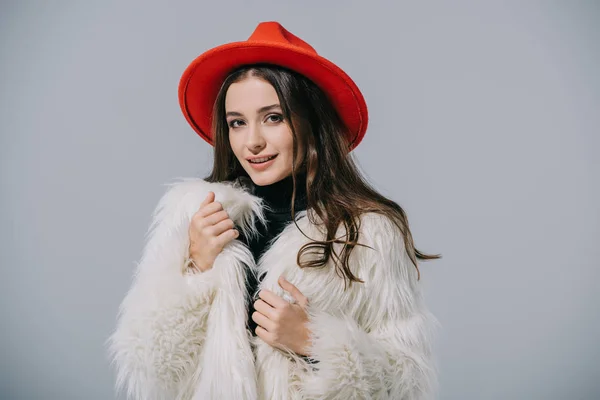 Sorridente ragazza elegante in posa cappotto di pelliccia alla moda e cappello rosso, isolato su grigio — Foto stock