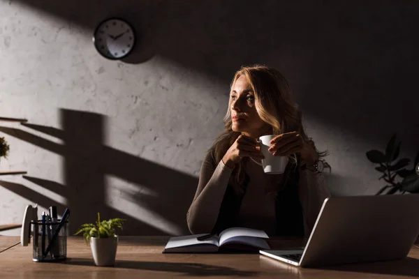 Attraktive Geschäftsfrau sitzt am Tisch und hält eine Tasse Kaffee — Stockfoto