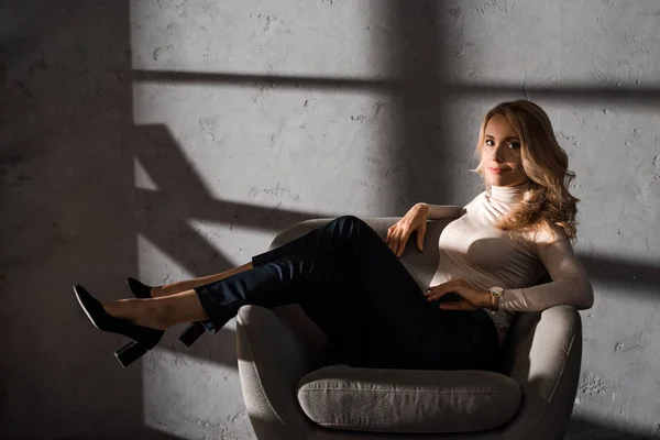 Attractive businesswoman sitting on armchair and looking at camera — Stock Photo