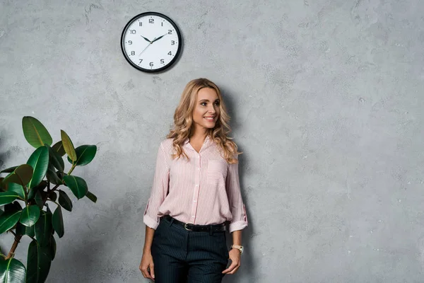 Attraente donna d'affari in camicia rosa sorridente e guardando altrove — Foto stock