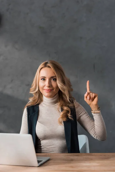 Mulher de negócios atraente sentado à mesa e mostrando sinal ideia — Fotografia de Stock