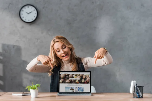 KYIV, UKRAINE - AUGUST 16, 2019: smiling businesswoman pointing with fingers at laptop with depositphotos website — Stock Photo