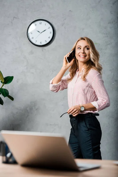 Mujer de negocios sonriente y atractiva en camisa hablando en smartphone - foto de stock