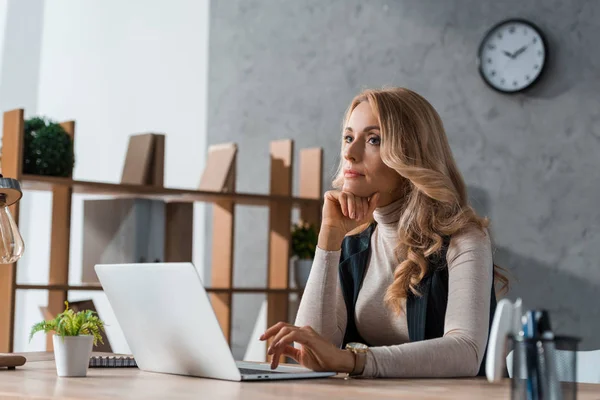 Attractive and dreamy businesswoman sitting at table and looking away — Stock Photo