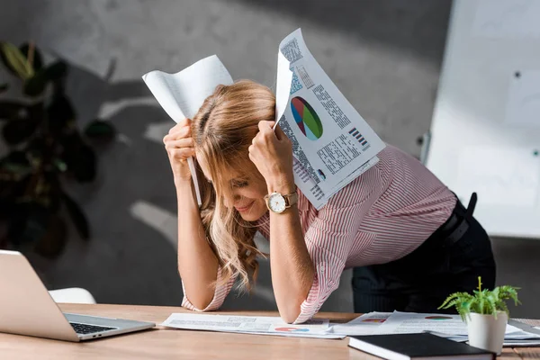 Привлекательная и грустная деловая женщина в рубашке, держащая бумаги в офисе — стоковое фото