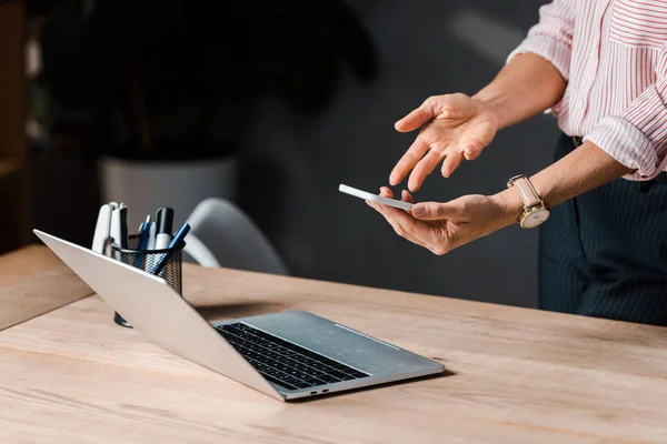 Vue recadrée de femme d'affaires en utilisant smartphone dans le bureau — Photo de stock