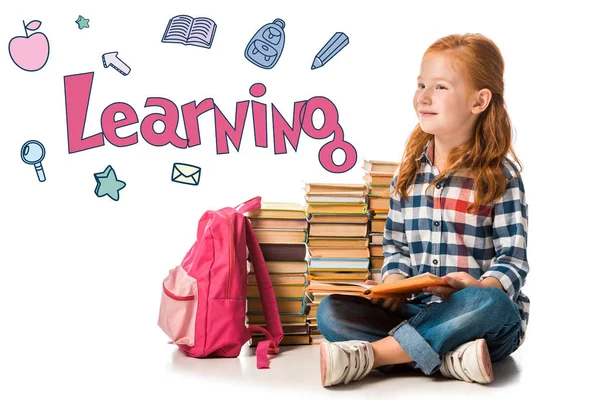Positive redhead schoolkid sitting near books and learning letters on white — Stock Photo