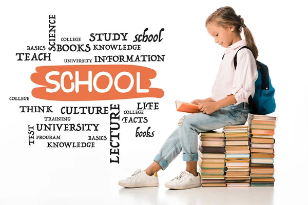 Alegre colegial sentado en los libros y la lectura cerca de letras en blanco - foto de stock