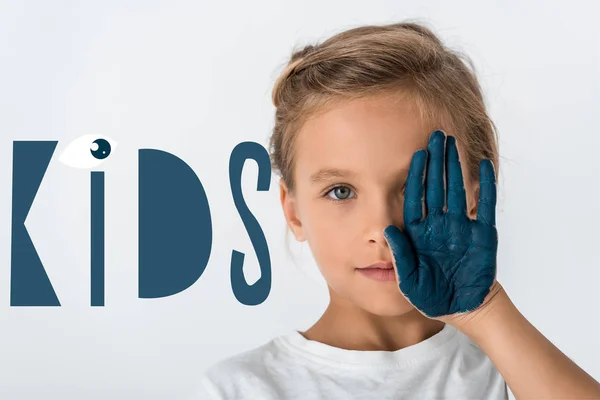 Niño con pintura azul en la mano cubriendo la cara cerca de niños letras en blanco - foto de stock