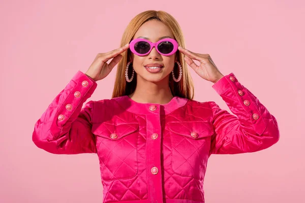 Vue de face de la fille afro-américaine élégante dans des lunettes de soleil isolées sur rose, concept de poupée de mode — Photo de stock