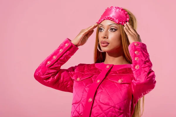 Donna afroamericana alla moda con maschera del sonno sulla testa isolata su rosa, concetto di bambola di moda — Foto stock