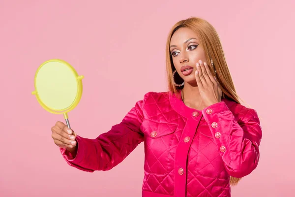 Bela, mulher americana africana na moda olhando para o espelho e tocando rosto isolado no rosa, conceito de boneca de moda — Fotografia de Stock