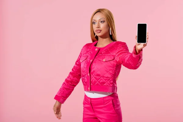 Attraktive, stylische Afroamerikanerin hält Smartphone isoliert auf rosa, Modepuppenkonzept — Stockfoto