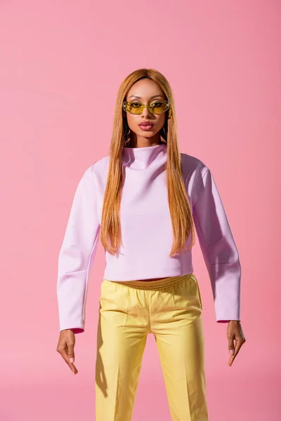 Front view of stylish, blonde african american woman standing isolated on pink, fashion doll concept — Stock Photo