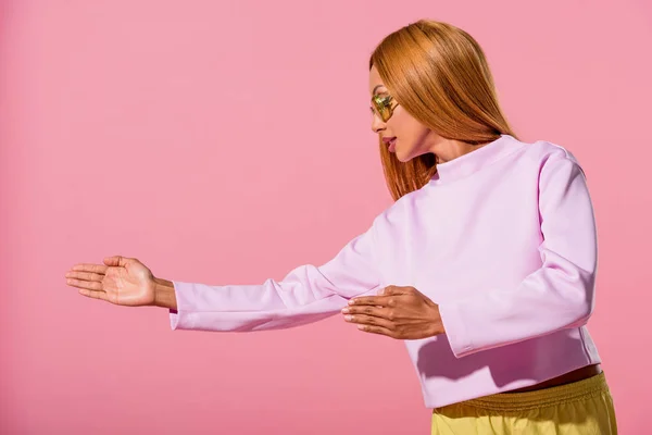 Модная блондинка-американка, жестикулирующая на розовой концепции куклы — стоковое фото