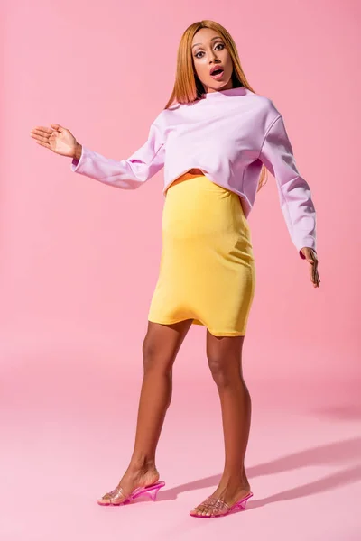 Incinta, donna afroamericana scioccata guardando la fotocamera su sfondo rosa, concetto di bambola di moda — Foto stock