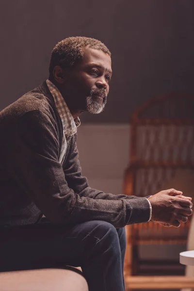 Solitario, anziano uomo afroamericano distogliere lo sguardo mentre seduto sul divano — Foto stock