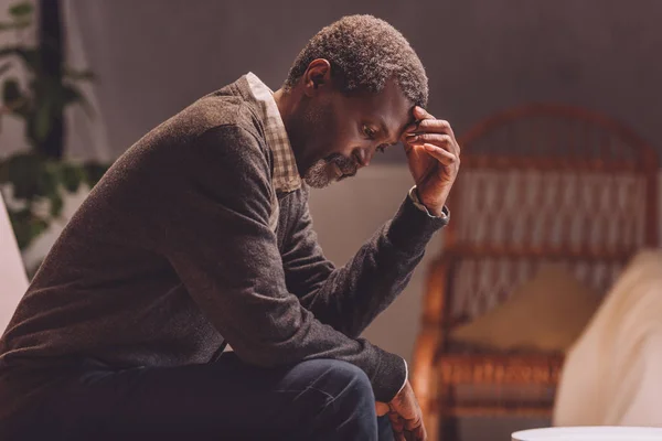 Aîné, homme afro-américain déprimé assis avec la tête inclinée — Photo de stock