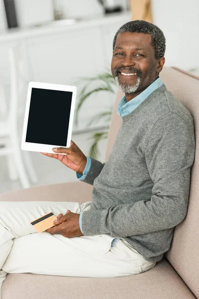 Sorridente afro-americano segurando cartão de crédito e mostrando tablet digital com tela em branco — Fotografia de Stock