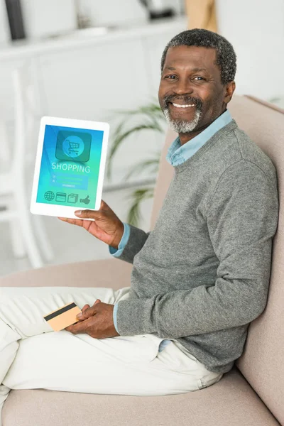 Smiling african american man holding credit card and showing digital tablet with online shopping  app on screen — Stock Photo