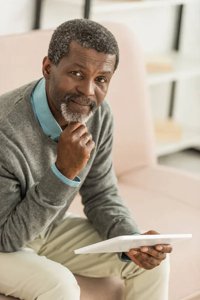 Pensive african american holding digital tablet while looking at camera — Stock Photo