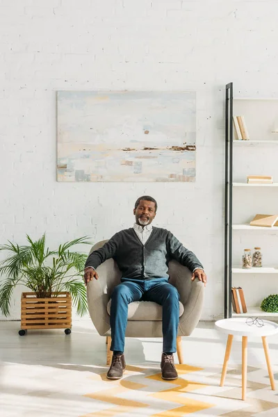 Homem americano africano sênior sentado no sofá na espaçosa sala de estar — Fotografia de Stock