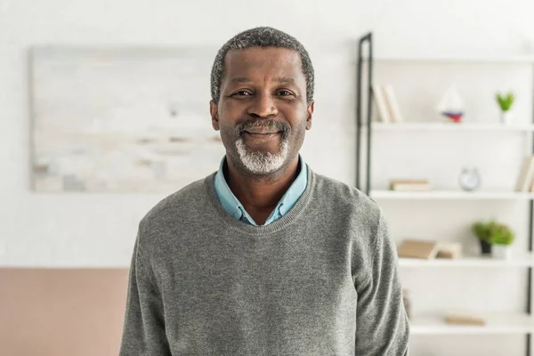 Веселий афроамериканський чоловік у сірому пуловері, посміхаючись на камеру — стокове фото