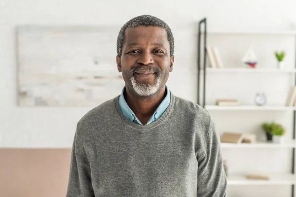 Homme afro-américain joyeux en pull gris souriant à la caméra — Photo de stock