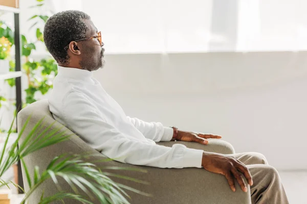 Anziano, elegante uomo africano americano seduto in poltrona e guardando altrove — Foto stock