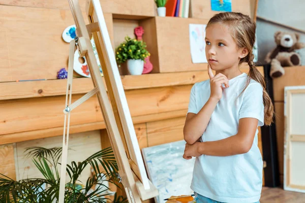 Nachdenkliches Kind schaut auf Staffelei in Kunstschule — Stockfoto