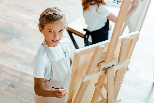 Вид симпатичного малыша, смотрящего на камеру в художественной школе — стоковое фото