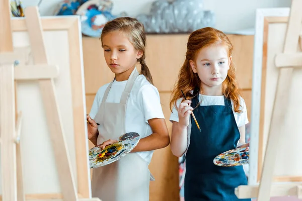 Selective focus of kids with multicolored palette near canvas — Stock Photo