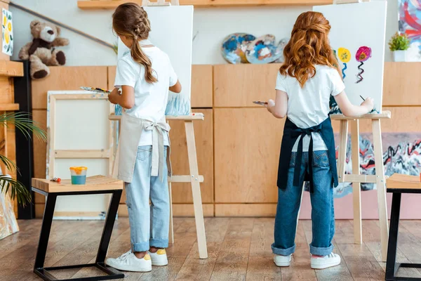 Vue arrière des enfants tenant la palette tout en peignant sur toile — Photo de stock