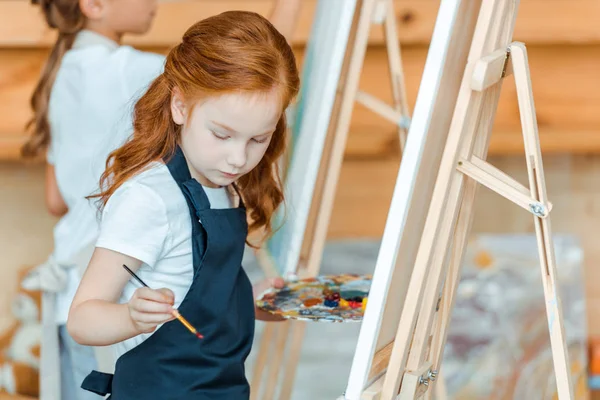 Selective focus of cute kid standing and painting in art school — Stock Photo