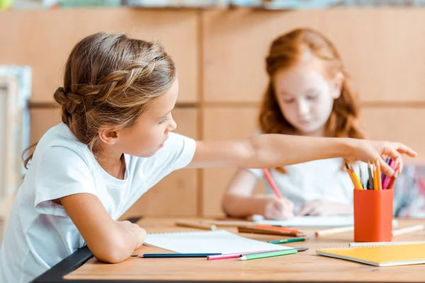 Selective focus of kid taking color pencil near redhead child — Stock Photo