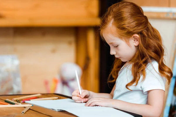 Lindo pelirroja niño dibujo en papel en arte escuela - foto de stock