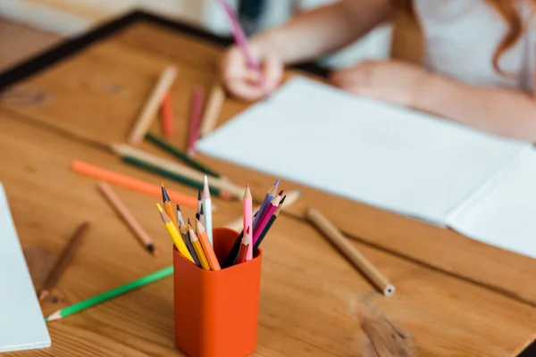 Selective focus of color pencils near kid and paper on table — Stock Photo