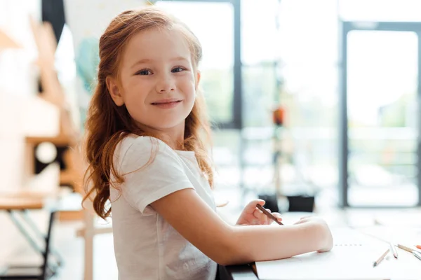 Fröhliches rothaariges Kind lächelt und blickt in die Kamera — Stockfoto