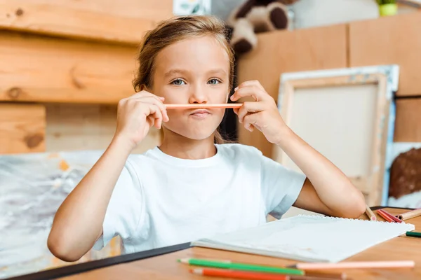 Messa a fuoco selettiva del bambino carino che tiene la matita di colore vicino al viso — Foto stock