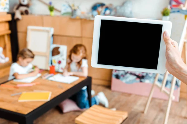 Vista ritagliata della donna che tiene tablet digitale con schermo vuoto vicino ai bambini — Foto stock