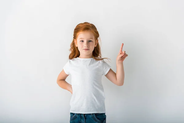 Mignon rousse enfant regardant caméra et pointant du doigt sur blanc — Photo de stock